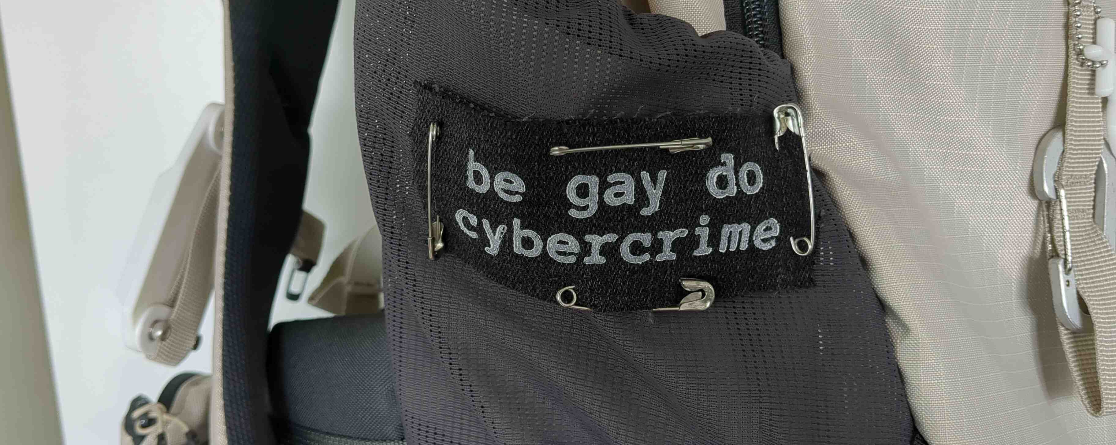 patch attached to a bag. It says "be gay do cybercrime"