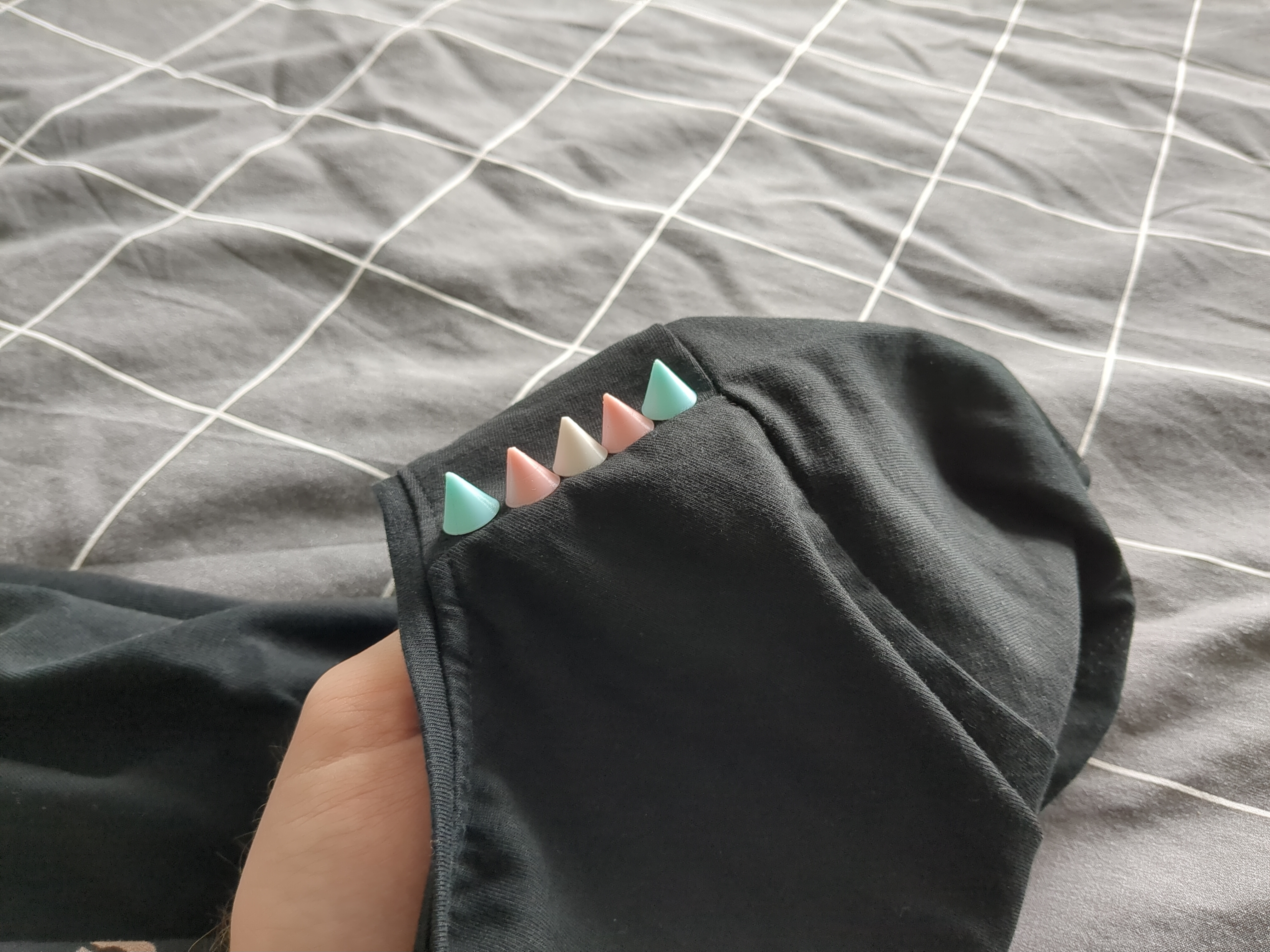 A row of trans flag coloured studs on black fabric